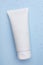 Wet tube of face cleansing product on light blue background, top view