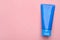 Wet tube of face cleansing product on pink background, top view. Space for text