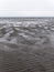 Wet wavy sand on the seashore at low tide on a cloudy day. Gloomy seaside landscape. The harsh nature of the north of Europe. The