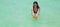 Wet young woman with super long hair in turquoise sea water holding big starfish in hands