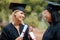 Weve finally graduated. Two young college graduates holding their diplomas while wearing cap and gown.