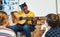 Weve got a future musician among us. a young girl sitting and playing the guitar for her classmates in the classroom at