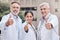 Weve got this. a group of doctors showing a thumbs up in the city.