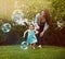 Weve got some bubbles to chase after, Mom. a mother and her adorable little daughter playing with bubbles outside.