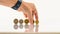 Whand places complete set of euro coins upright on a white table top - with reflection