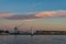 Wharf with hoisting crane and lighthouse at dusk