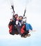 This is what birds must feel like. Portrait of two people doing tandem paragliding in mid-air.