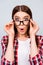 What?! Cute amazed brunette girl in glasses and checkered casual