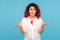 What do you want? Portrait of annoyed hipster woman with fancy red hair standing with raised hands