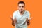 What do you want? Portrait of disgruntled annoyed brunette man standing with raised hands. indoor studio shot isolated on orange