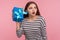 What`s inside? Portrait of woman in striped sweatshirt holding gift box near ear and listening, guessing birthday surprise