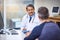 What seems to be the matter today sir. a cheerful mature male doctor seated at his desk while consulting a patient