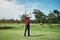 What a shot. a cheerful young male golfer lifting up his hands in success of playing a good shot outside during the day.