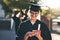 Whats graduation day without sharing it on social media. a young woman using a mobile phone on graduation day.