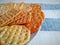 Wheat crackers on plate on linen striped white blue tablecloth.