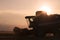 Wheat field in backlight with a combine harvester in action