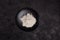 Wheat flour in a black plate on a dark background. The ingredient. Bakery products