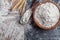 Wheat flour with scoop and wheat ears on kitchen board top view. Ingredient for baking