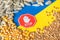 Wheat grains, corn and sunflower seeds on the yellow and blue flag of Ukraine with stop sign