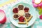 Wheat round bread rolls with jam and chocolate paste in the shape of a flower on a blue plate. Milk and a toy