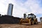 Wheel bulldozer with bucket at street in the city during construction of the road. Tractor during excavation work is underway to