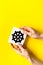 Wheel of dharma - Buddhist religion symbol - in hands on yellow table top view copy space