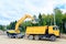 The wheel excavator loads the earth with a bucket to the body of a multi-ton dump truck on the construction site