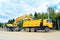 The wheel excavator loads the earth with a bucket to the body of a multi-ton dump truck on the construction site