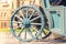 wheel of a green wooden carriage standing on paving stones near a medieval castle, selective focus