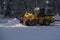 Wheel loader is removing snow at night during snowfall. Selective focus, blurred.
