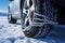 Wheel with snow chains tackles deep winter snow, maintaining control in challenging conditions.