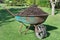 Wheelbarrow full of compost on green lawn in garden.