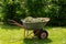 Wheelbarrow with grass and leaves. Gardening. Planting care. Seasonal trimming of trees, bushes and other perennial plants