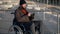 wheelchair-bound man on walk in city, using social networking in smartphone