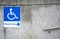 Wheelchair ramp sign for the disabled on  dirty pebbles stone wall texture with steel railing in public place