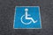 Wheelchair symbol on asphalt road, above view. Disabled parking permit