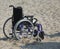 Wheelchair with wheels locked in the sand of the beach