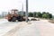 A wheeled bulldozer with a bucket is conducting road construction work in the city.