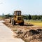 A wheeled bulldozer clears the ground with a metal shield.