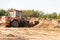 A wheeled dozer collects soil into a bucket in a quarry.