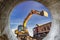 A wheeled excavator loads a dump truck with soil and sand. An excavator with a high-raised bucket against a cloudy sky View from