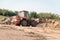 Wheeled tractor bulldozer drips the earth in the quarry.