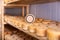 Wheels of sheep cheese on shelves in ripening room with copy space