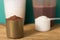 Whey Protein. Front view of two scoops with chocolate and vanilla powder and shakers on rustic wooden table. Solid color: green.