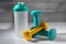 Whey protein mixer accompanied by two dumbbells