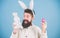 Which one came first. Easter bunny delivering colored eggs. Bearded man with bunny toy and Easter egg. Hipster with long