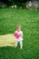 Whimpering child stands on a green lawn and holds a plastic food container in his hands