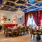 A whimsical Alice in Wonderland-themed dining room with oversized teacup chairs, playing card decorations, and chandelier2