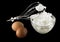 Whipping eggs with whisk and eggs isolated on black background