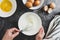 Whipping white eggs with whisk, in a palte. Top view of woman& x27;s hands mixing eggs, cooking pastry